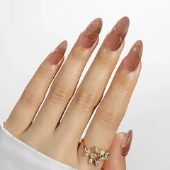 Elegant nude coffin nails with gold accents, showcasing a stylish ring on a manicured hand.