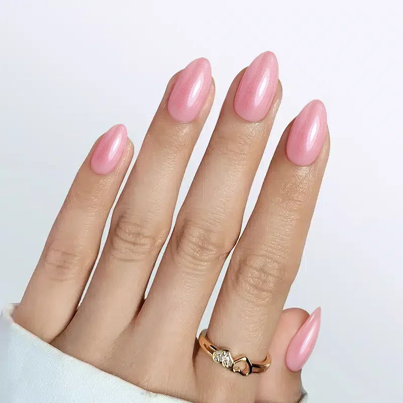 Stylish long almond-shaped nails in glossy pink finish with a gold ring on a hand.