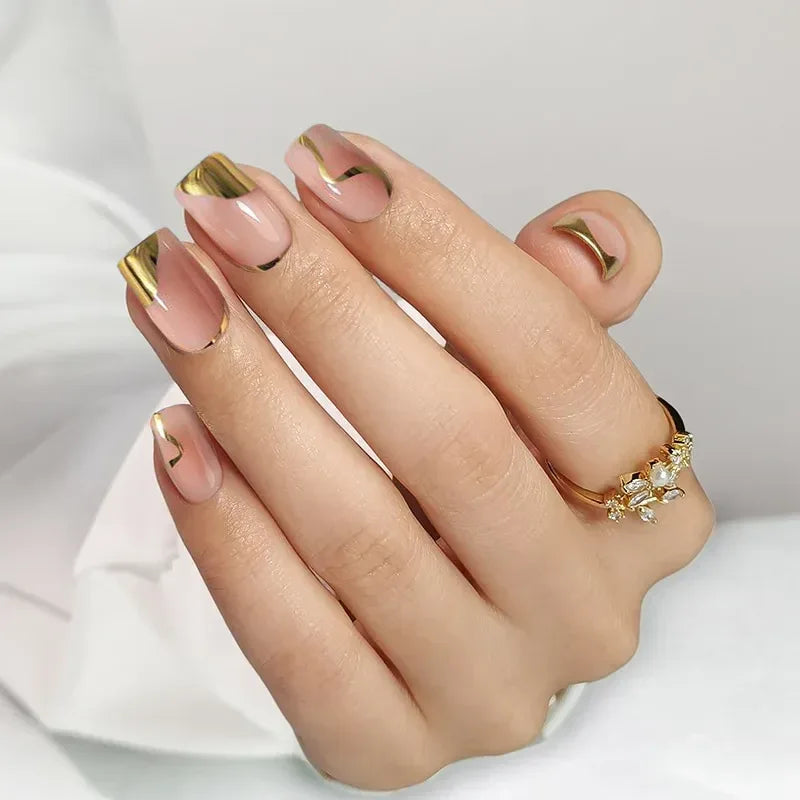 Stylish nude nails with gold tips and accents, showcasing elegant design and manicure perfection.