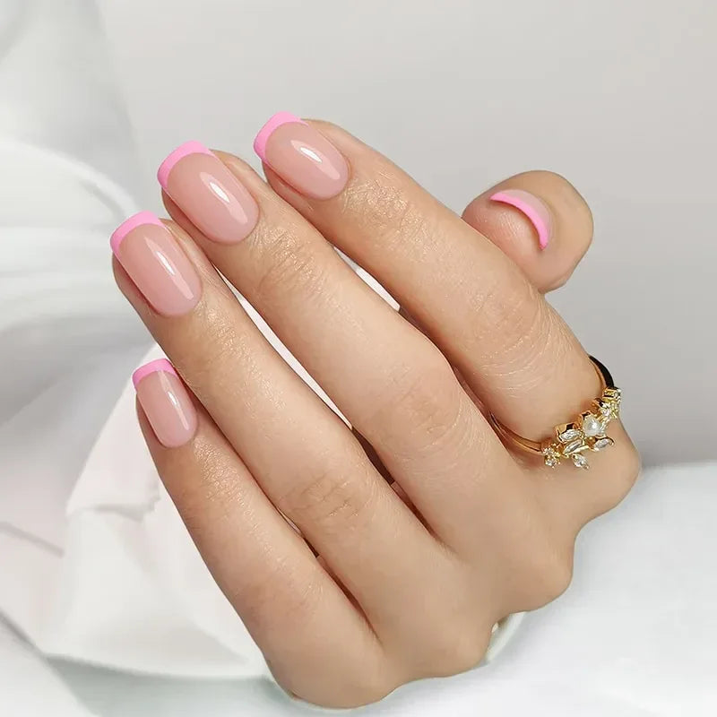 Nude nails with pink tips, natural finish, featuring stylish gold ring with gems.