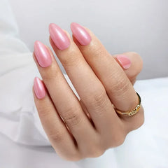 Elegant long pink nail polish with a glossy finish on a hand wearing a gold ring.