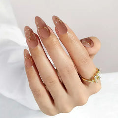 Elegant nude manicure with gold accents and a stylish ring, perfect for a chic look.