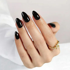 Stylish black glossy almond-shaped nails with a golden ring, perfect for chic occasions.