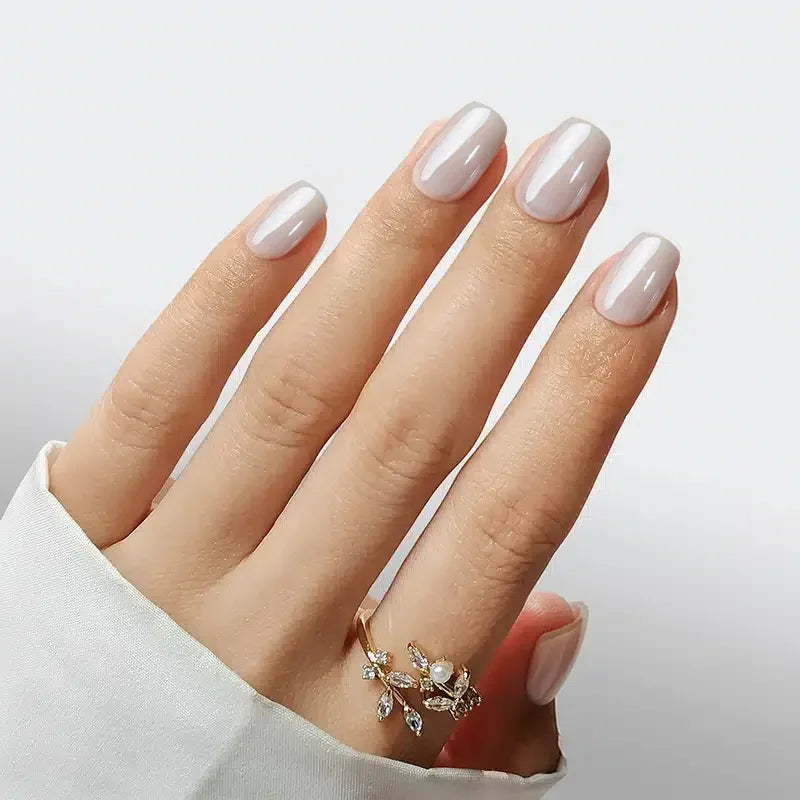 Elegant light pink manicure with glossy finish, featuring delicate floral ring on a hand.