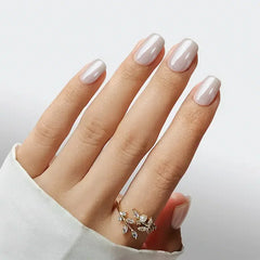 Elegant light pink manicure with glossy finish, featuring delicate floral ring on a hand.