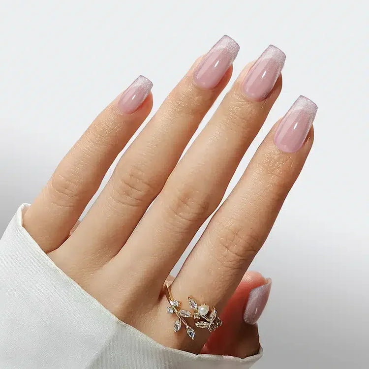 Elegant long pink ombre nails with a glossy finish, paired with a delicate gold ring.