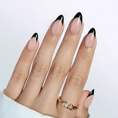 Elegant almond-shaped nude nails with striking black tips, showcasing a stylish and modern manicure.